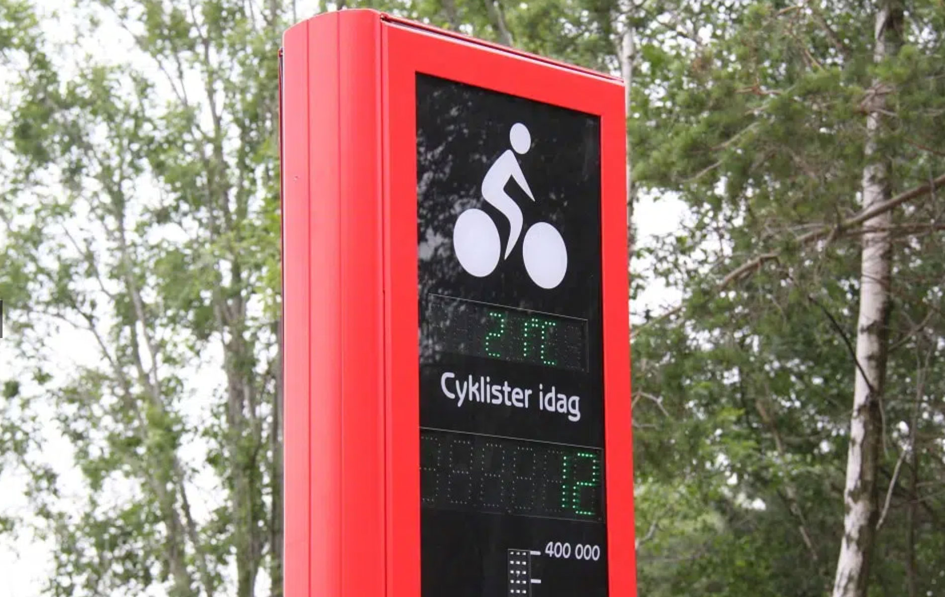 En röd cykelbarometer som står längs cykelbanan.