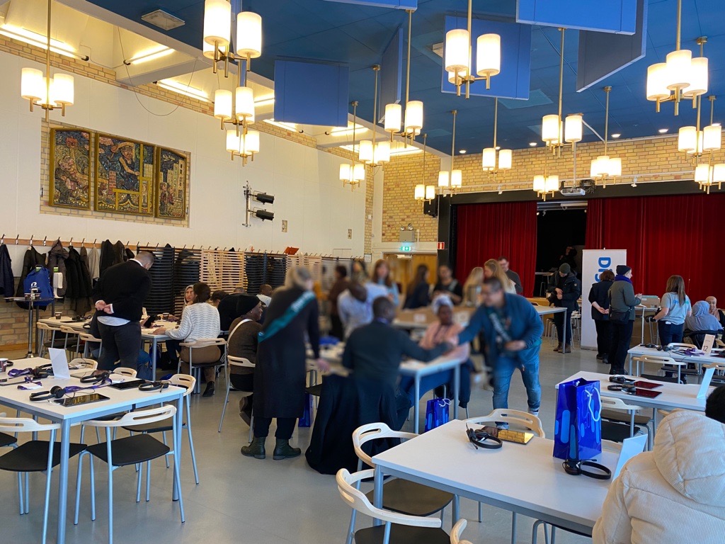 Foto från
Tappströmsskolans matsal. Deltagarna sitter runt olika bord och pratar. 