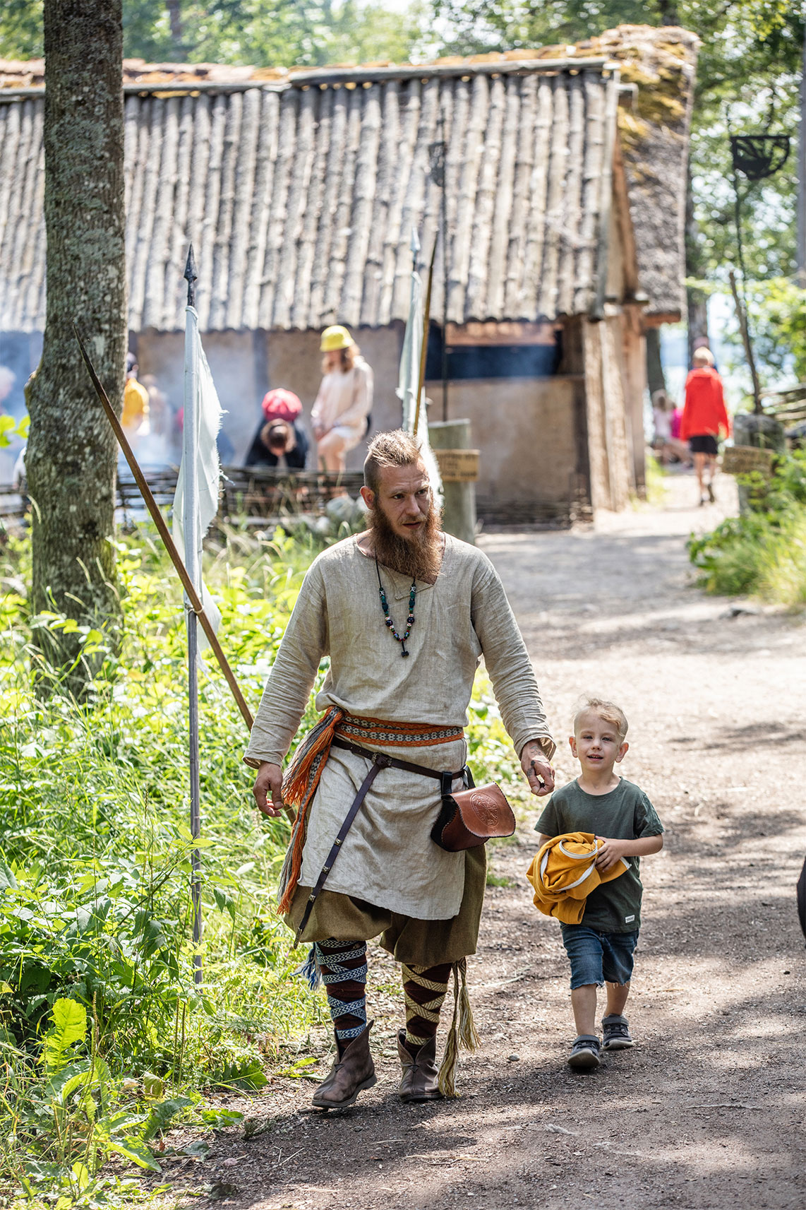 Vuxen och barn som går utomhus i vikingaklädsel.