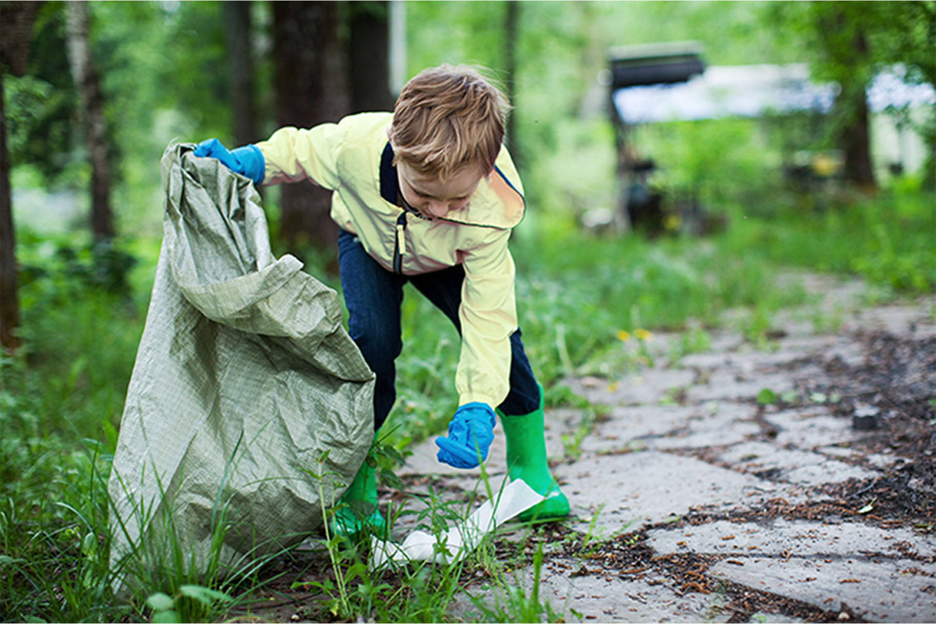 Ett barn plockar upp skräp från marken.