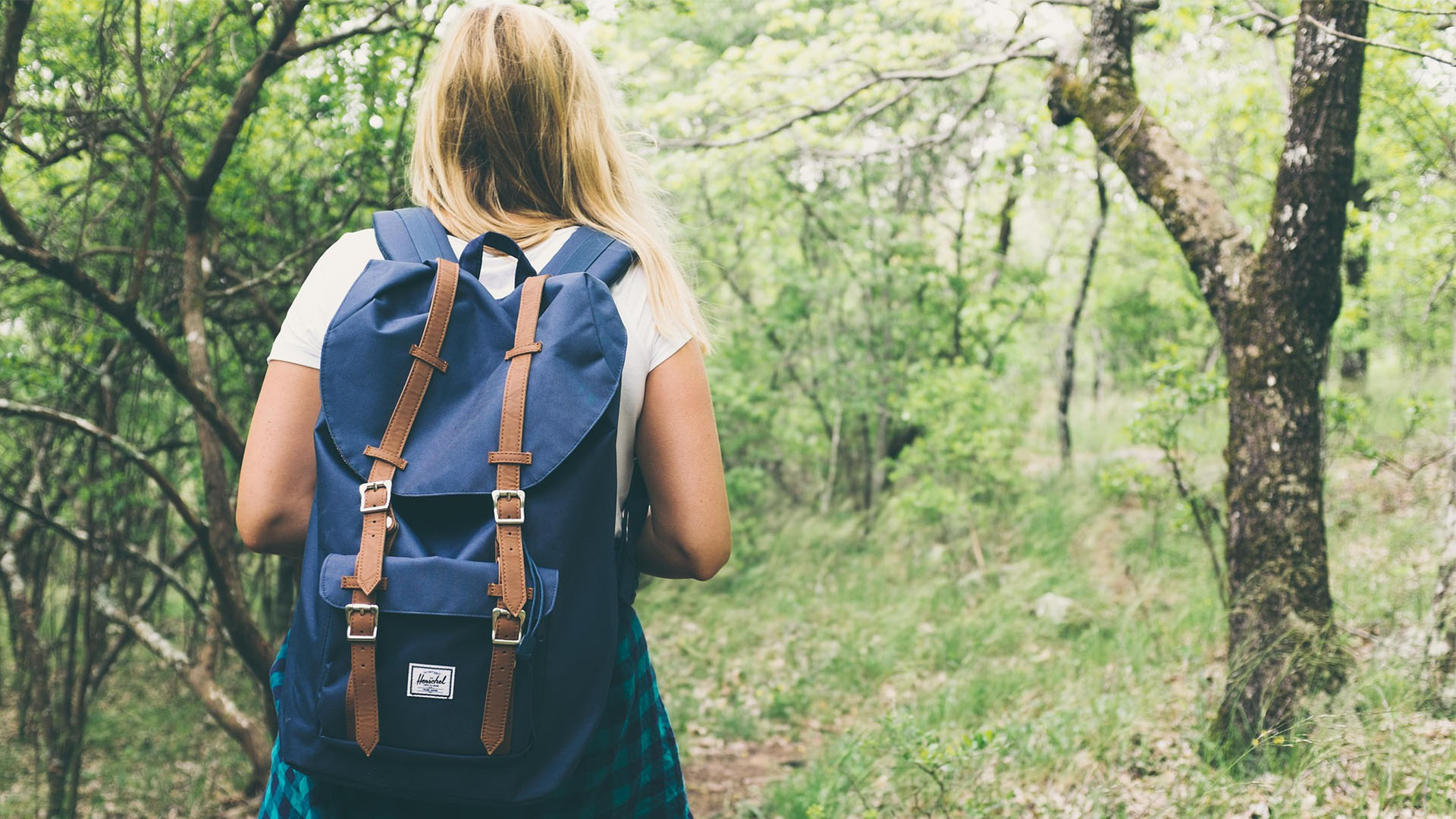 Kvinna vandrar i skogen med ryggsäck