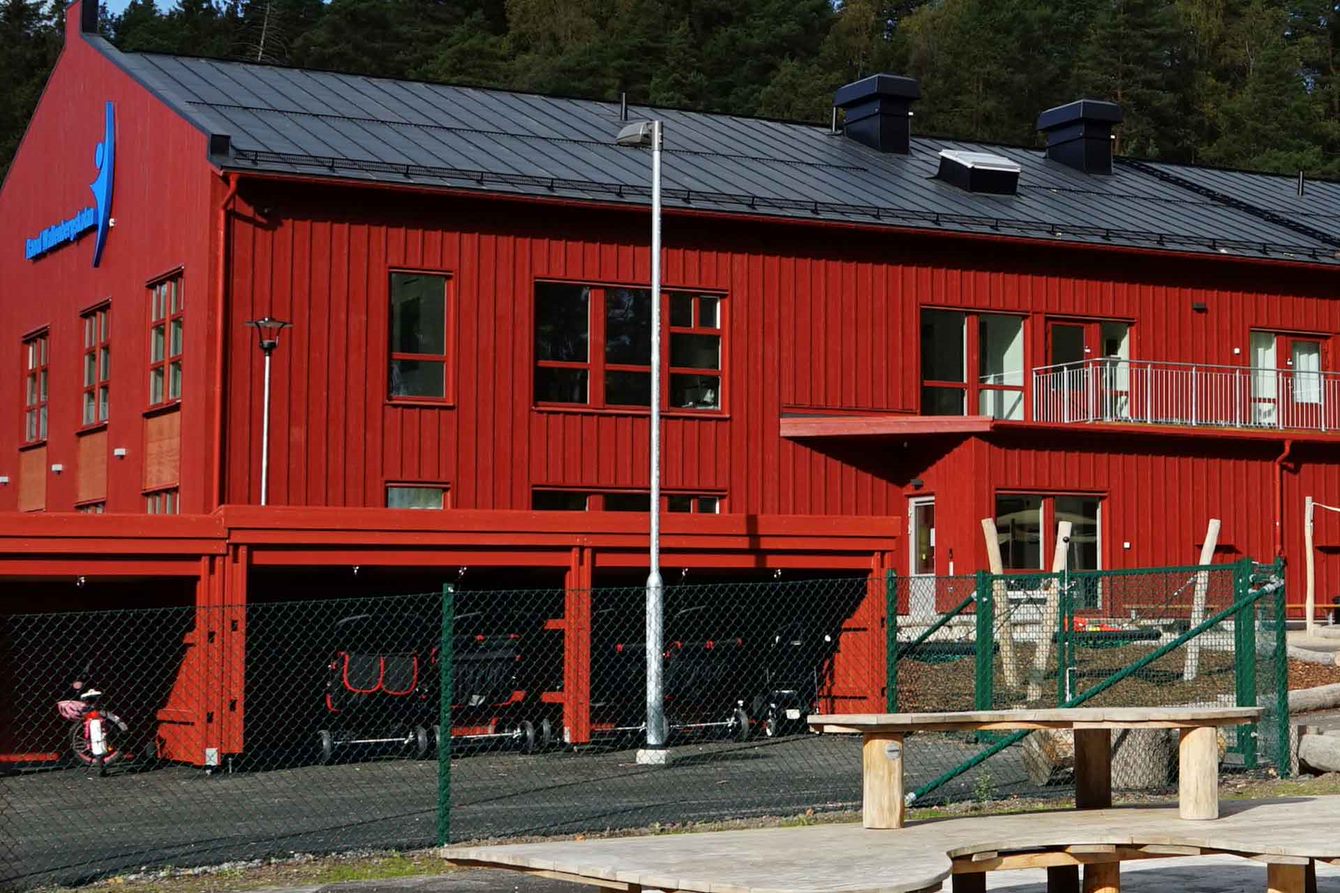 En röd skola i två plan med en lekplats i förgrunden