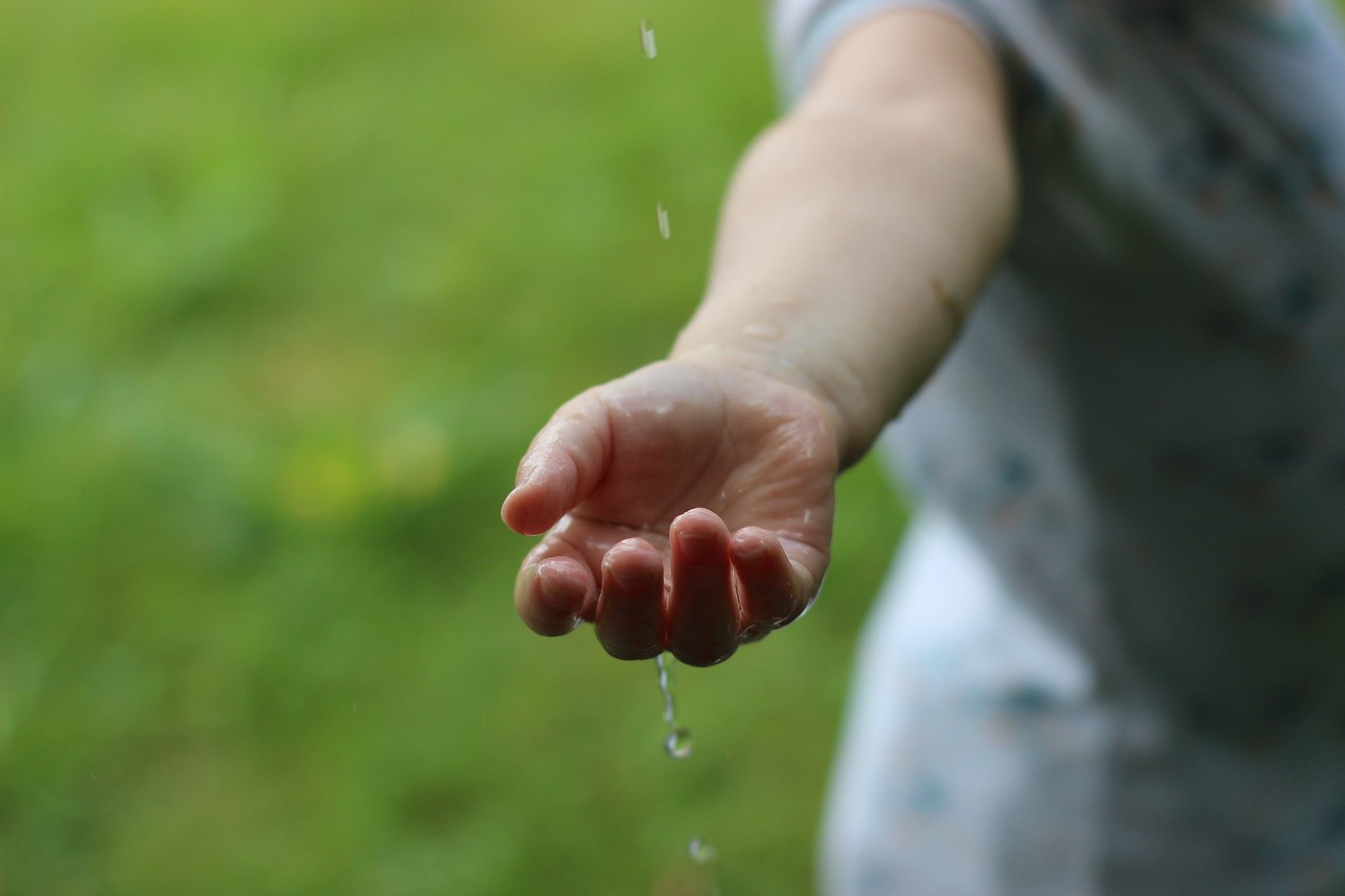 Ett barns hand som känner på en vattenstråle.