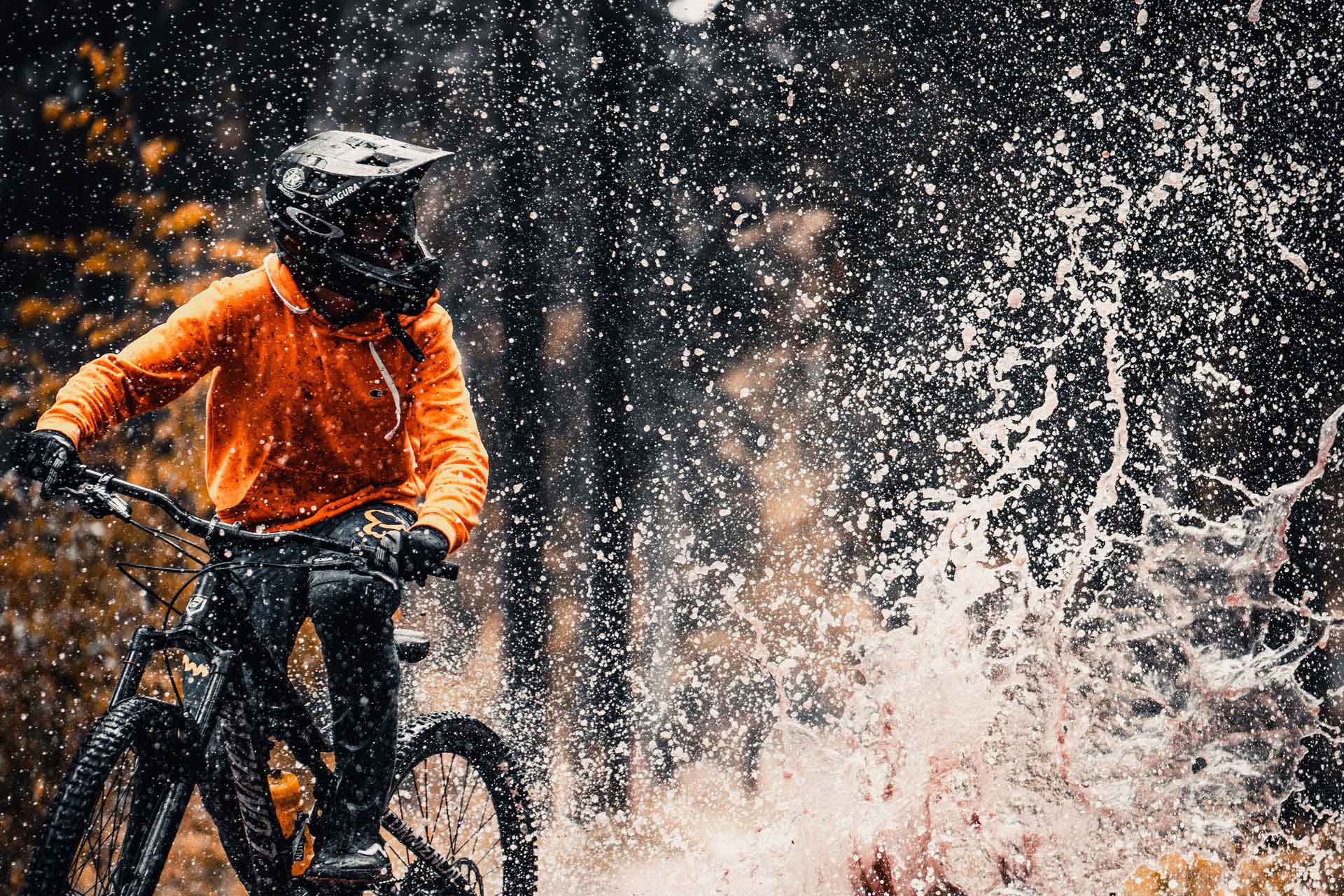 Person i outdoor-kläder som åker mountainbike genom vatten.