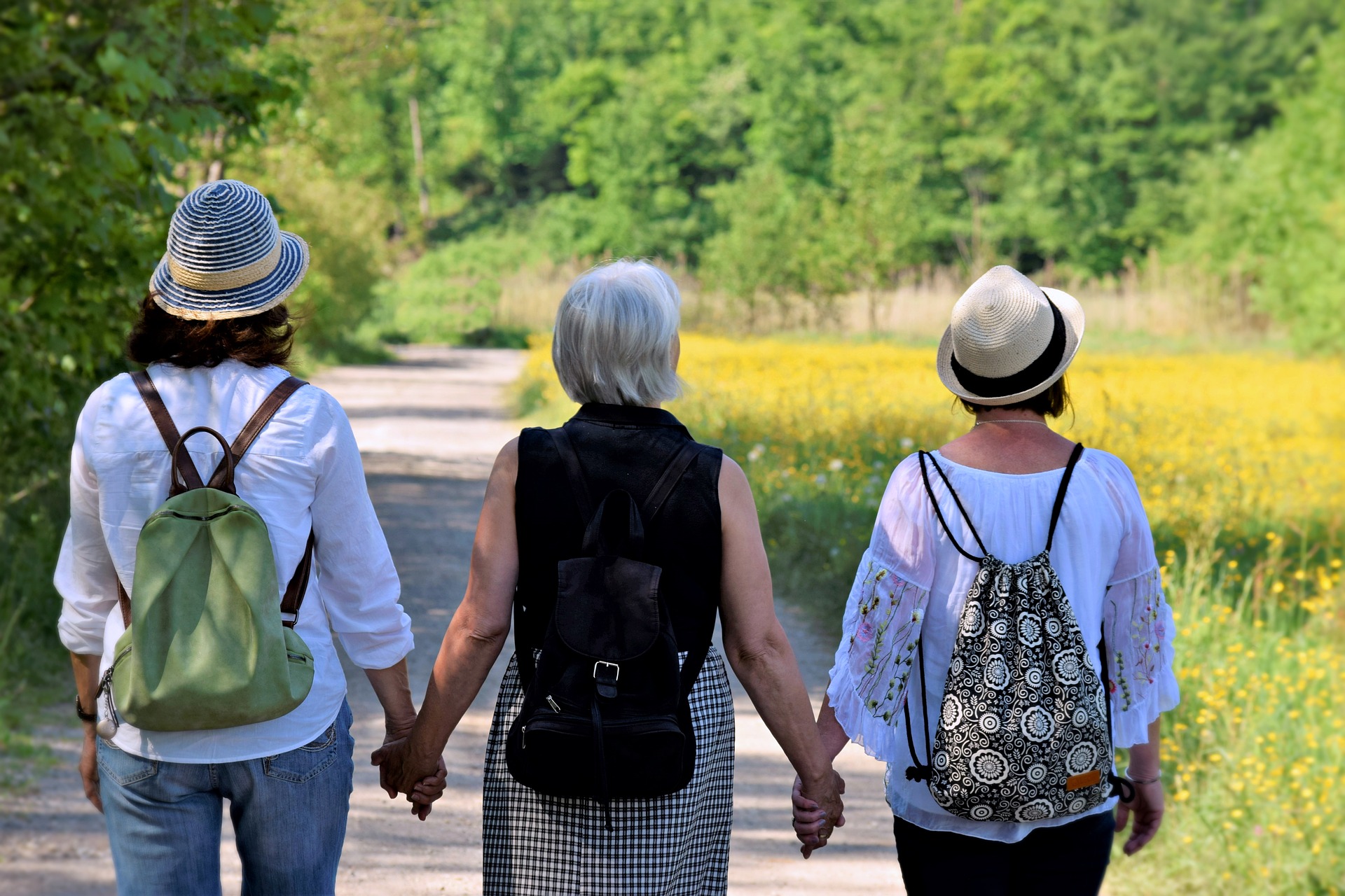 Tre äldre kvinnor går på en väg, på sommaren. 