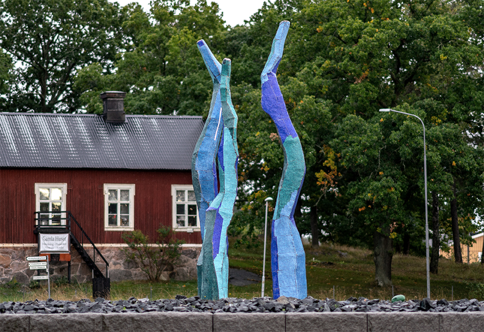 Konstverket Nattfåglar i skymningen. Tre avlånga former klädda i blå mosaik slingrar mot skyn.