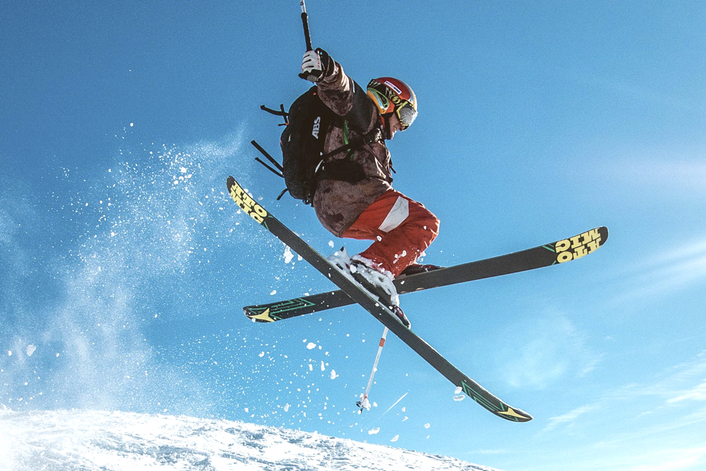 En skidåkare hoppar i skidbacken och korsar skidorna.