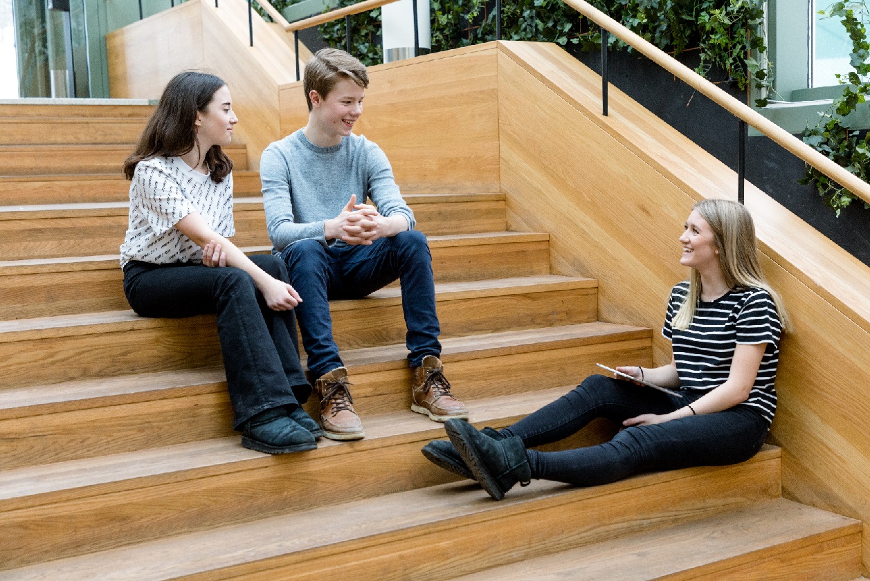 Tre ungdomar sitter på en trappa