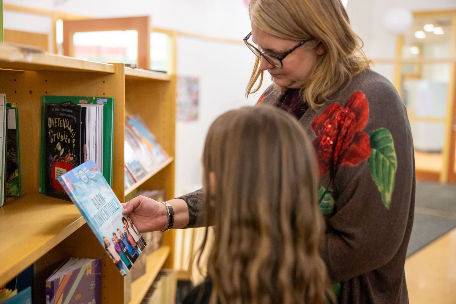 Skolbibliotekarie Katarina visar elev en bok