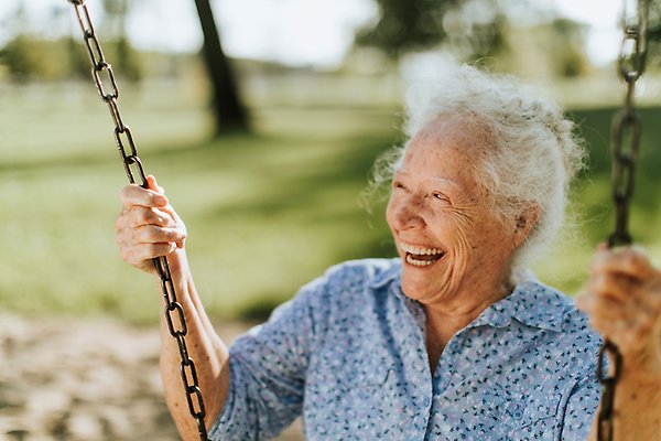 Äldre kvinna som gungar och ler.