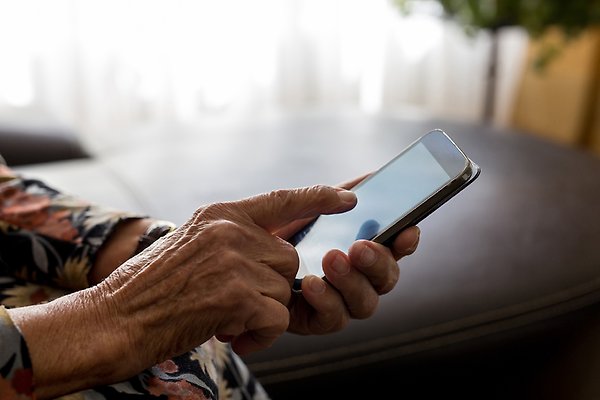 Mobiltelefon som hålls i handen av en äldre person